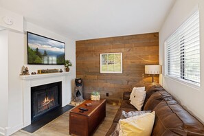 Un salon avec une cheminée, un canapé, une table basse et un téléviseur fixé au mur.