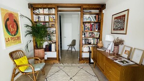 A cozy living room with a large bookshelf, a comfortable chair, a coffee table, and a rug. - Villa D'architecte Avec Piscine au Coeur D'un Parc (Villeneuve-lès-Avignon)