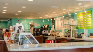 A coffee shop interior with a menu board for ice cream flavors, a coffee machine, and a counter with a glass display case.
