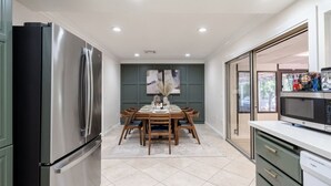 A modern kitchen with a stainless steel refrigerator, a dining table set for four, and a microwave on the counter.