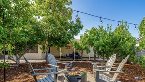 An outdoor seating area with Adirondack chairs, a fire pit, and string lights.