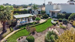 Un jardín bien cuidado con un patio, setos recortados y una variedad de plantas.