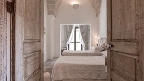 Un dormitorio con una cama grande, un espejo y vistas a una ventana con cortinas.