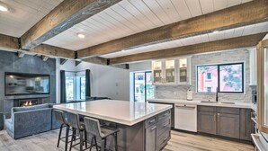 Une cuisine moderne dotée d’un grand îlot central, d’appareils électroménagers intégrés et d’un pare-feu en pierre.