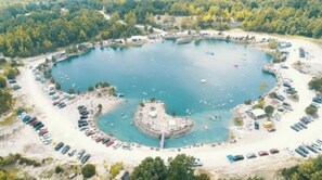 An aerial view of a circular lake surrounded by a parking area and a small island with a dock.
