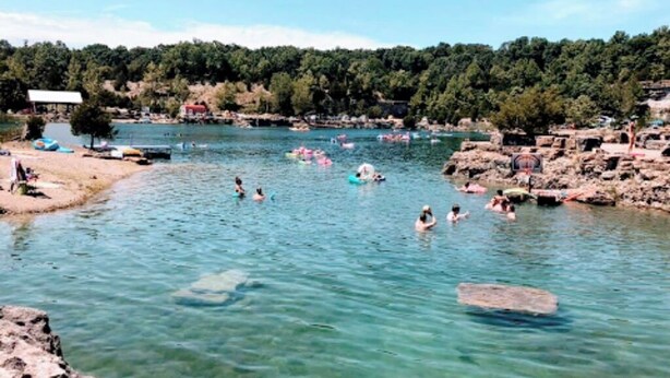 A river with people swimming and floating. There are boats and a dock on the left. - Quaint little home (La Grange)