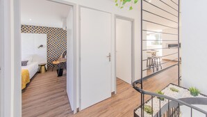 A modern interior with a staircase, a bed with a yellow blanket, a patterned wall, and a dining area with a table and chairs. - Le Foncillon 4* Apartment at the foot of the beach (Royan)