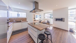 A modern kitchen with a central island, a built-in stove, and a large window. - Le Foncillon 4* Apartment at the foot of the beach (Royan)