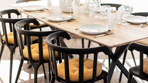A dining table with chairs, a potted plant, and glassware. - Le Foncillon 4* Apartment at the foot of the beach (Royan)