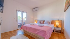 Ein Schlafzimmer mit Bett, Nachttischen, einem weißen Teppich und einer Glasschiebetür, die zu einem Außenbereich führt.