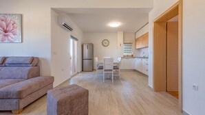 Eine moderne Wohnung mit Wohnbereich, Küchenzeile und Essplatz.