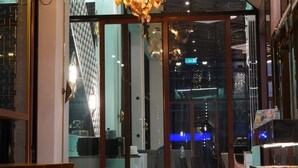 Un interior moderno con una lámpara única, puertas de cristal que dan a un comedor y vistas de la ciudad.
