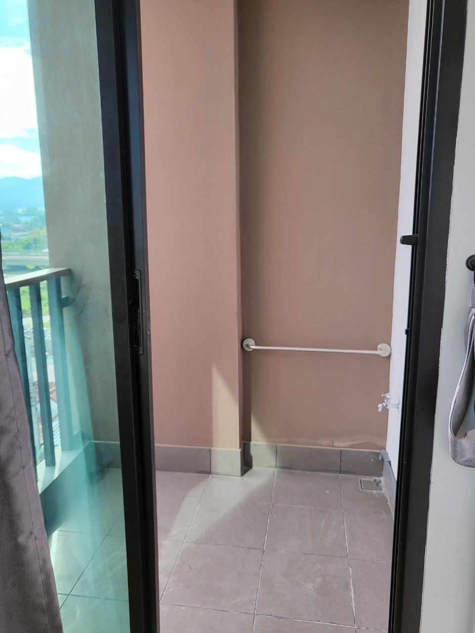 A balcony with a metal handrail, a glass door, and a view of a building.
