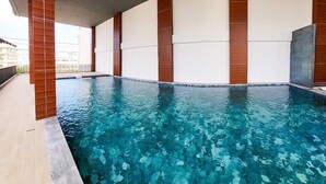 Una piscina interior moderna con agua azul cristalina, rodeada de paredes blancas y detalles de madera.