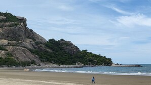 Una playa con un acantilado rocoso y cielo despejado.