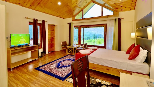 A bedroom with a bed, a TV, a desk, and a view of the outdoors. - Zaara resort, hidden resort in manali (Manali)