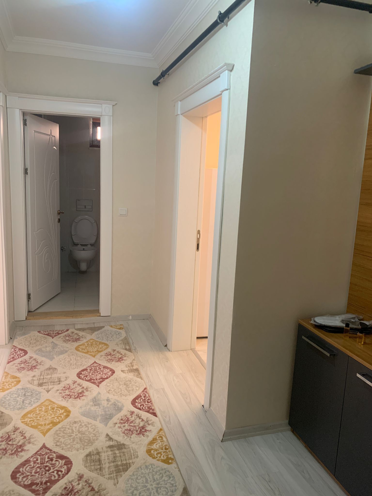 Un pasillo con un rug adornado, un armario de madera y una puerta que da a un baño.