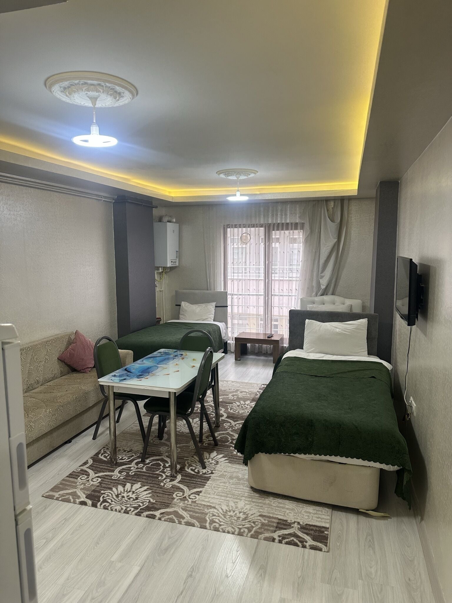 Habitación de hotel pequeña con cama, una mesita y un sofá.