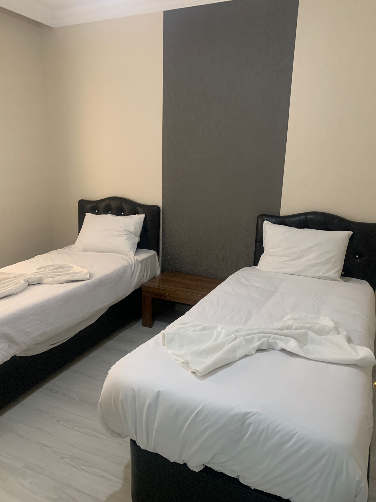 Ein Hotelzimmer mit zwei Einzelbetten, jeweils mit einem Nachttisch aus Holz und weißer Bettwäsche.