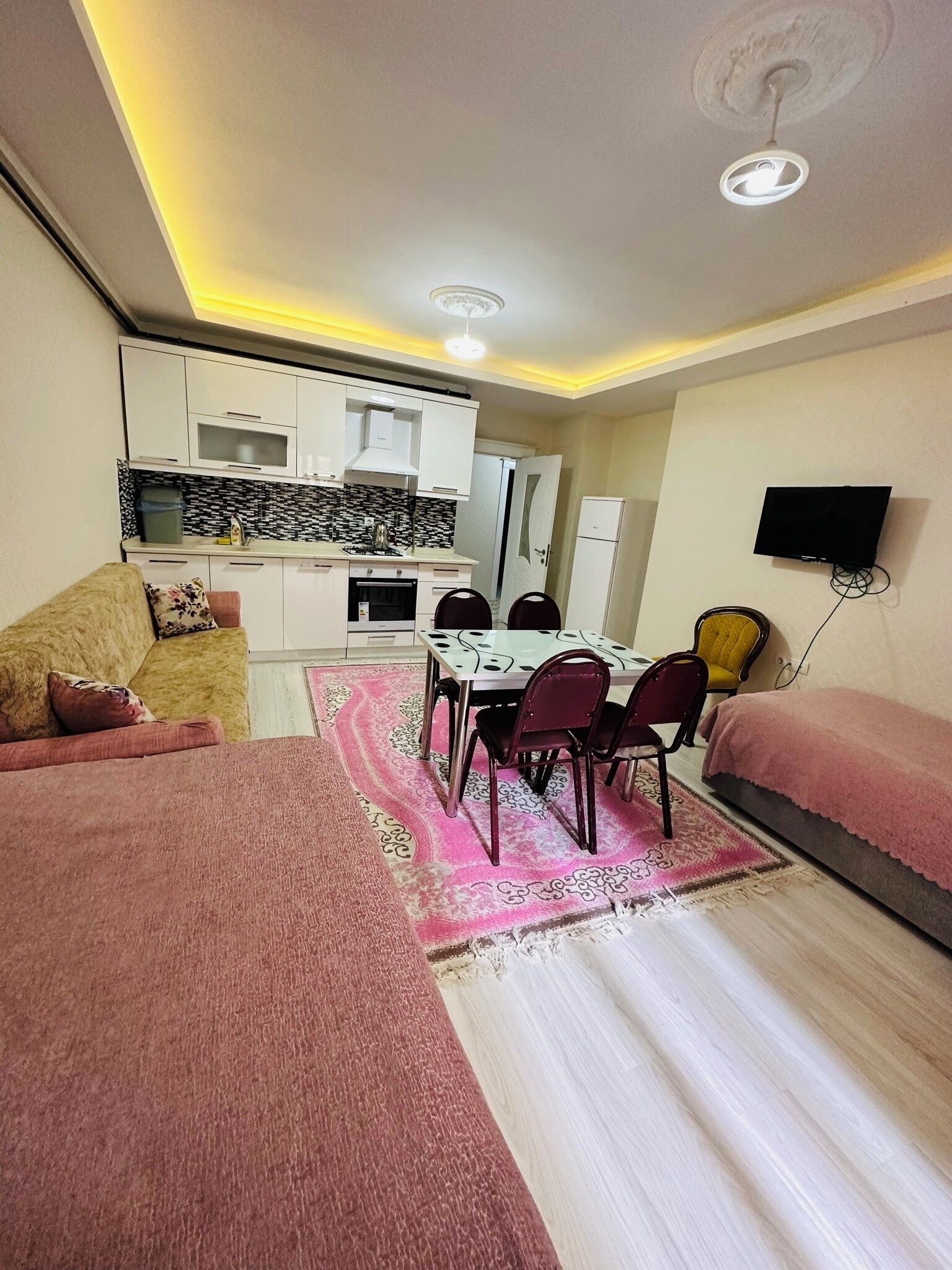 Un espacio habitable compacto con kitchenette, comedor y dos camas.