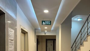 Un pasillo de hotel con alfombra estampada, una escalera y una señal de salida.