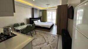 Una habitación de hotel con cama, escritorio con sillas, televisor y ventana con cortinas.