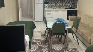 Un espacio habitable compacto con comedor, kitchenette y sofá.