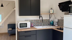 Een moderne keuken met zwarte kasten, een magnetron, een koffiezetapparaat en een broodrooster. Er is een houten aanrecht en een spoelbak.
