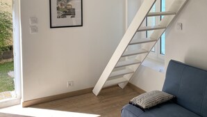 Een moderne woonkamer met een blauwe bank, een ingelijste foto aan de wand en een houten plafond.