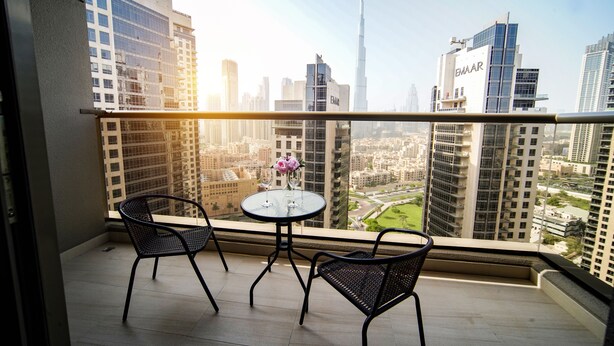 Un balcón con dos sillas y una mesa, con vista a un paisaje urbano con rascacielos.