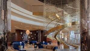 A luxurious lobby with a grand staircase, plush seating, and a chandelier. - Luton Vacation Homes - Paramount Midtown (Dubai)