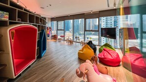 A modern interior with a large window, wooden flooring, and colorful seating areas. - Luton Vacation Homes - Paramount Midtown (Dubai)
