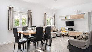 Un salon moderne comprenant un coin repas, un canapé, un téléviseur et un meuble.