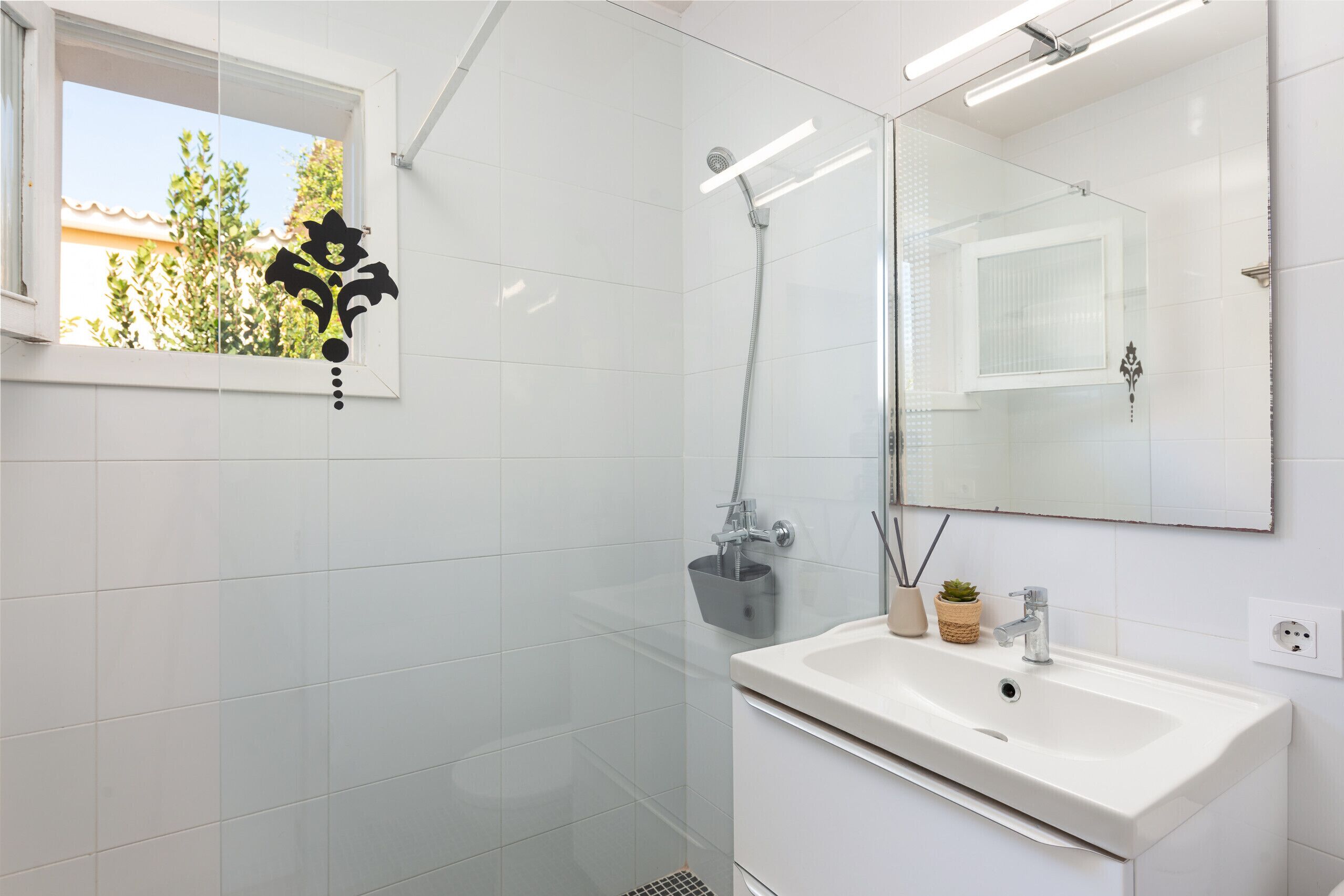 Une salle de bain moderne avec un lavabo blanc, un miroir et une douche.