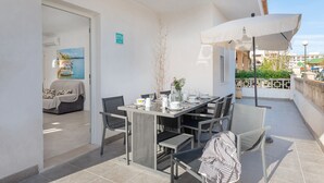 Un espace de restauration en plein air avec une table dressée pour quatre personnes, des chaises et un grand parasol.