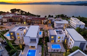 Un moderno complejo hotelero con varias construcciones, piscinas en la azotea y vistas al mar.
