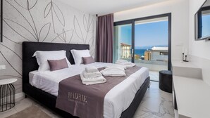 Une chambre d’hôtel moderne dotée d’un grand lit, offrant une vue sur la mer et présentant un design minimaliste.