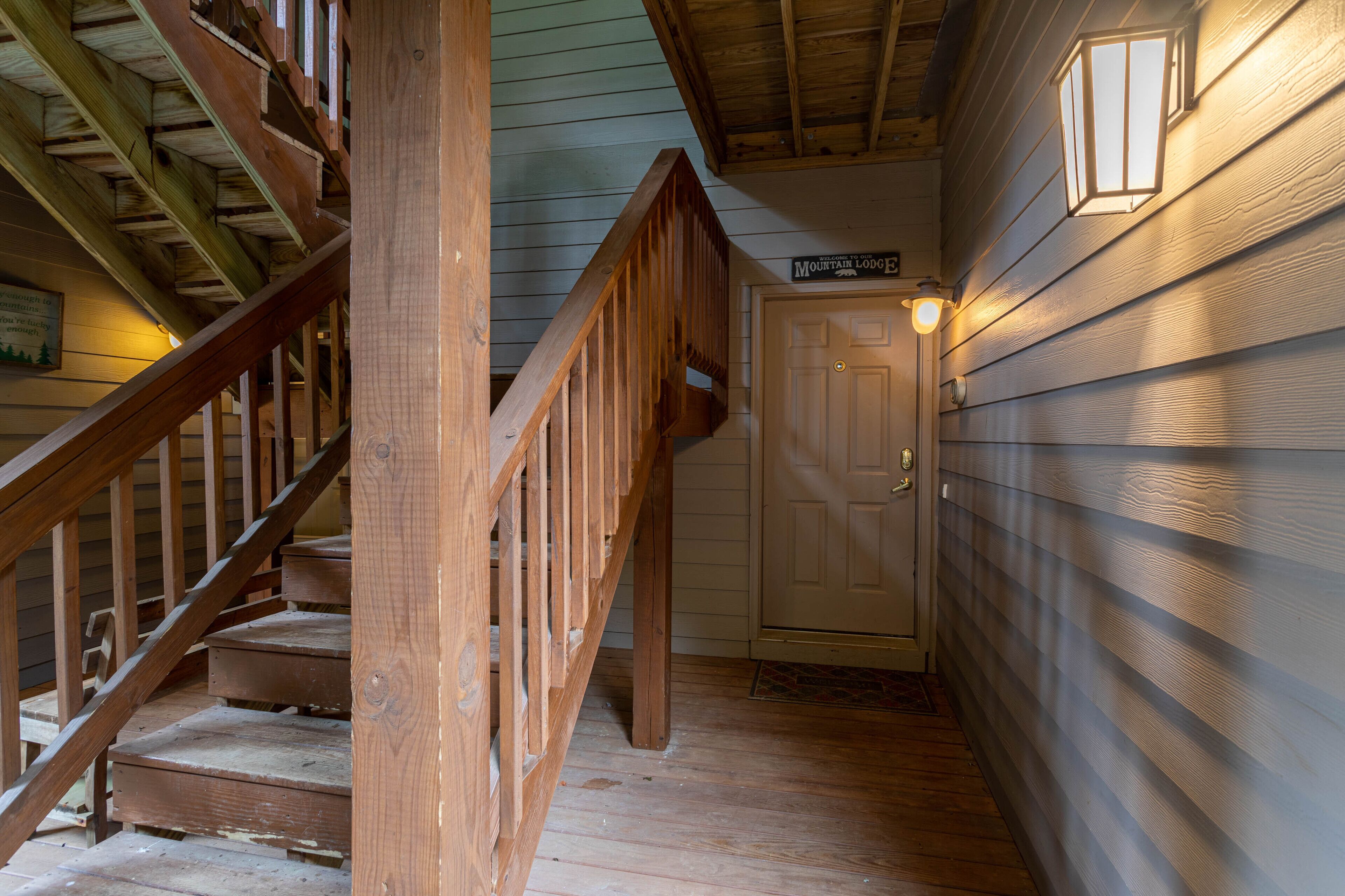 A wooden staircase leading to a door with a sign above it.