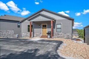 A two-story house with a stone foundation, a front porch, and a garage.
