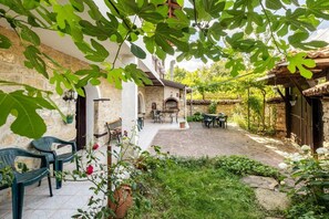 Un patio con suelo de piedra, mobiliario exterior y un horno de ladrillo.