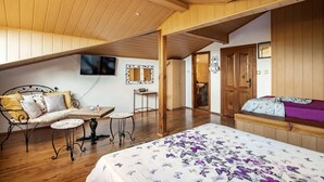 A bedroom with a bed, a desk, a chair, a television, and a bathroom visible through an open door. - Lovely 5-bed Authentic House in the Arbanasi (Veliko Tarnovo)