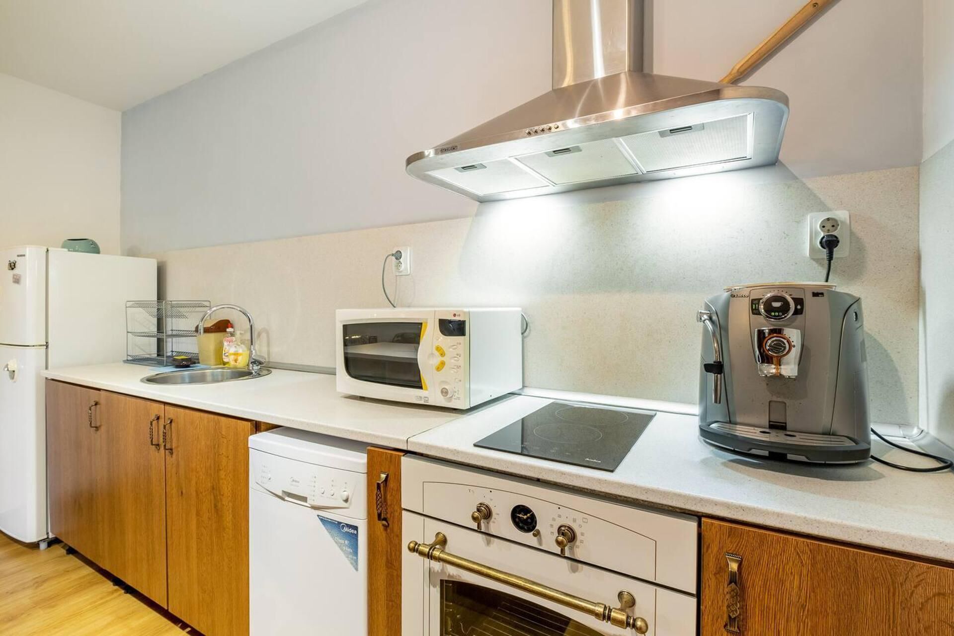 A compact kitchen with a built-in oven, a microwave, a coffee maker, and a refrigerator.