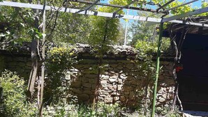 A stone wall with climbing plants, a pergola, and a rustic building. - Lovely 5-bed Authentic House in the Arbanasi (Veliko Tarnovo)