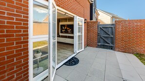 A brick house with a sliding glass door leading to a patio. - My Chester Luxury 3bedroom Home (Colchester)