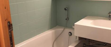 A bathroom with a bathtub, a sink, and a mirror.