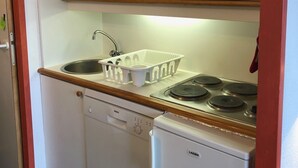 A compact kitchen with white cabinets, a Bosch dishwasher, a stove, and a microwave. - Studio 4 Personnes Proche des Pistes (La Plagne-Tarentaise)