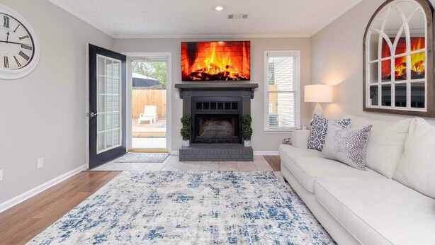 A living room with a fireplace, a clock, a sofa, and a rug. - Comfort Stay | 2BR 2BA | Private Patio | Near RAFB (Warner Robins)