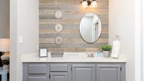 A bathroom with a wooden wall backsplash, a round mirror, and a sign reading "Powder Room". - Comfort Stay | 2BR 2BA | Private Patio | Near RAFB (Warner Robins)