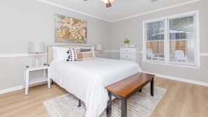 A bedroom with a bed, bedside tables, a ceiling fan, a window with blinds, and a painting on the wall. - Comfort Stay | 2BR 2BA | Private Patio | Near RAFB (Warner Robins)