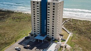 A high-rise building with a central blue section labeled "MUSTANG TOWERS". - Ocean View, Shared Pool/Hot Tub, Boardwalk to Beach (Port Aransas)
